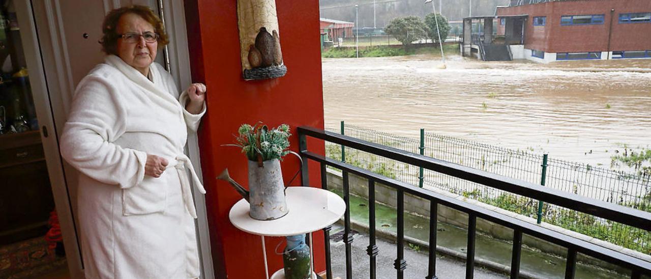 María Florina Miranda, a la puerta de su casa de Agones, en Pravia, con las instalaciones del polideportivo municipal (la piscina cubierta en primer término) a la derecha.