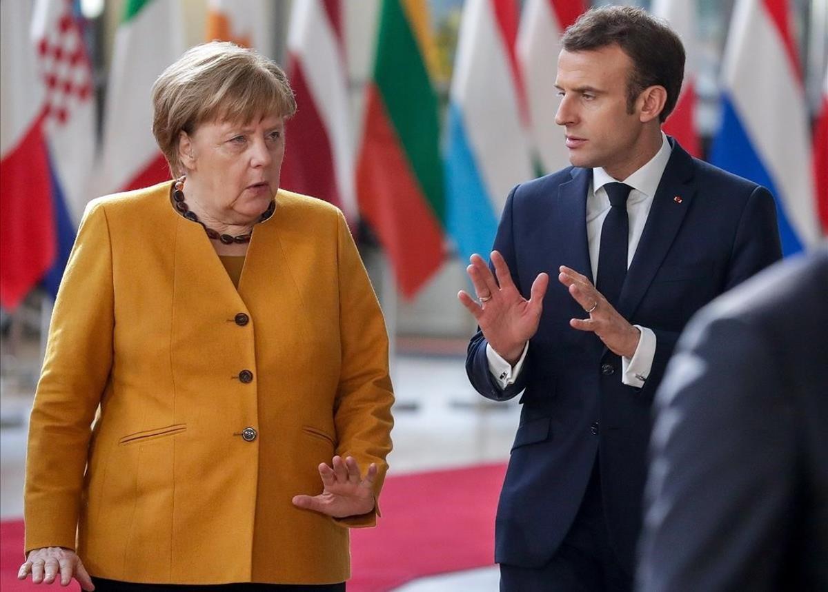 Angela Merkel  con Emmanuel Macron  mientras se dirigen a posar en una foto de familia de la cumbre del Consejo Europeo.