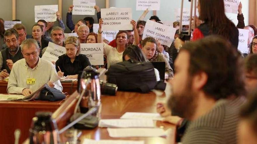 Público con carteles de protesta durante el pleno de ayer. // J. Lores