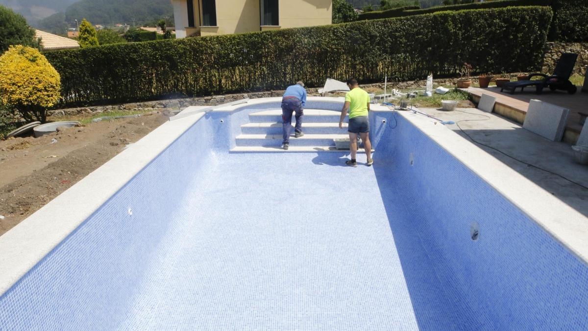 Dos operarios trabajando en la construcción de una piscina.
