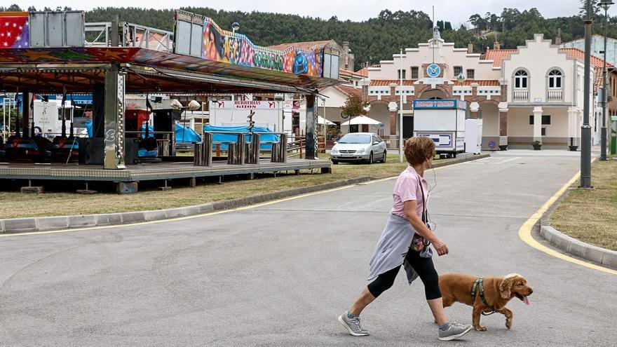 Una mujer pasea el perro cerca de las atracciones festivas en La Arena.