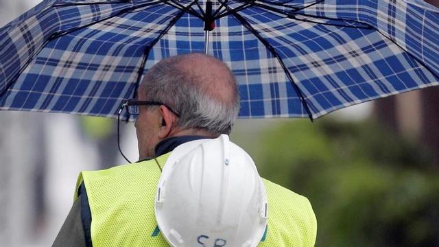 Un trabajador de la construcción se protege de la lluvia en Valencia.
