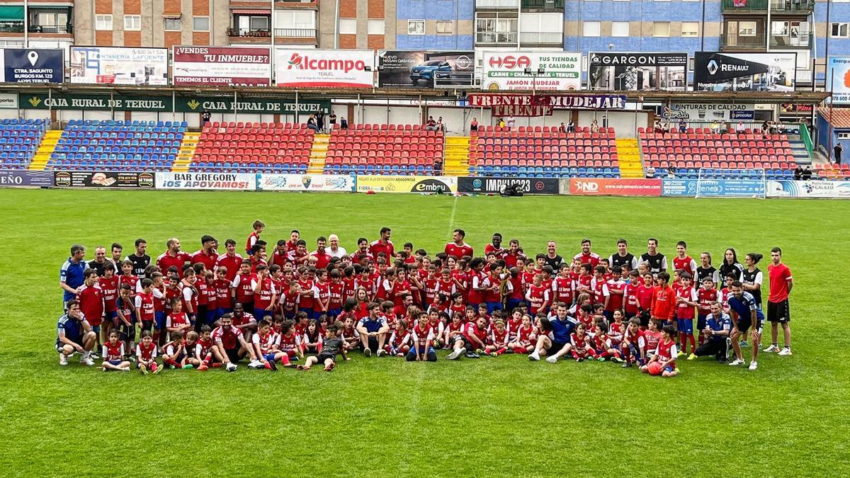 Los futbolistas del Teruel y los niños de la Escuela del club, sobre el verde del Pinilla.