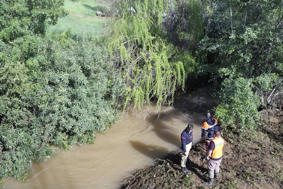 Dos efectivos de Protección Civil y un bombero observan el cauce del arroyo Pedroche este lunes.