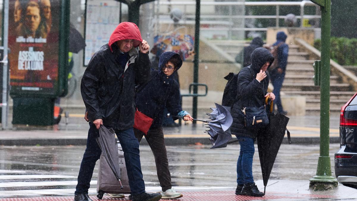 Varias personas tratan de cubrirse de la lluvia y el viento, a 20 de octubre de 2023, en Santander, Cantabria (España).