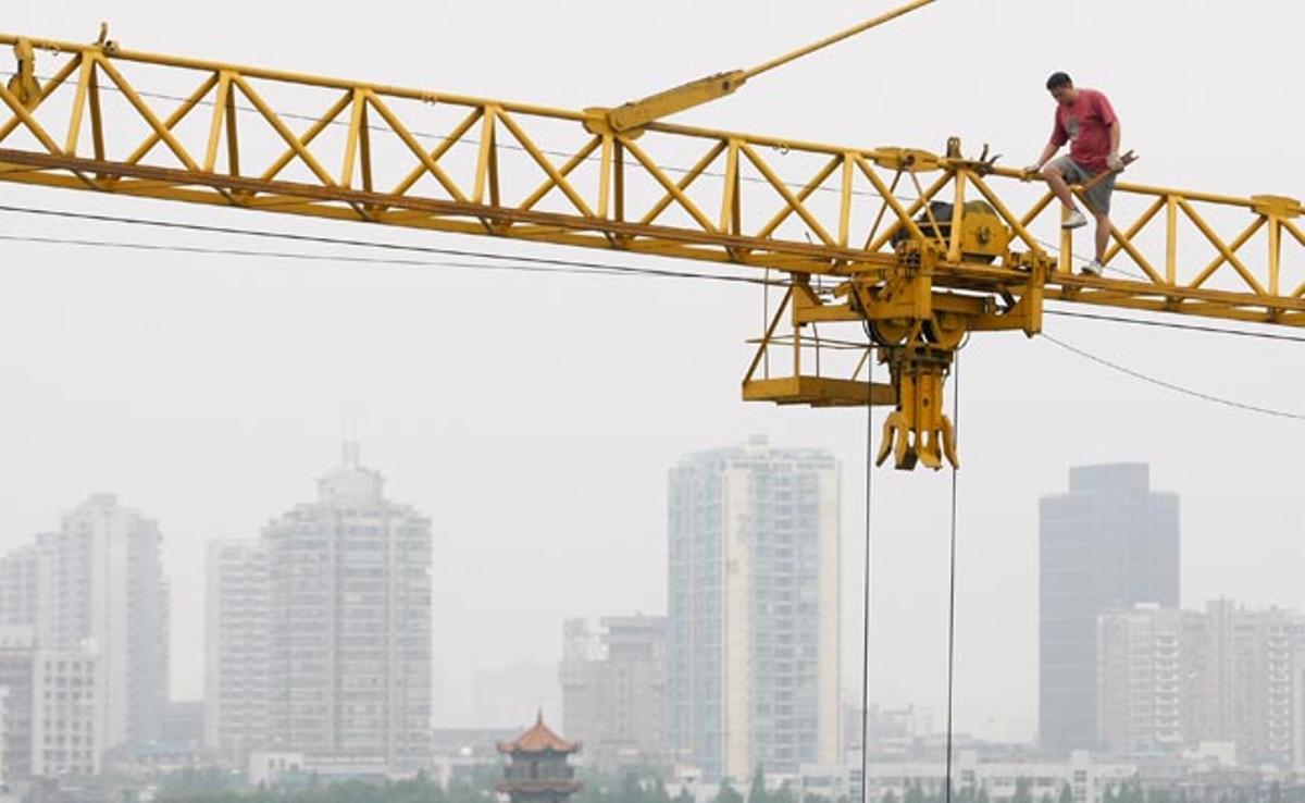 Un treballador de la construcció camina sobre una grua al districte financer de Hubei, província de Hubei, Xina.
