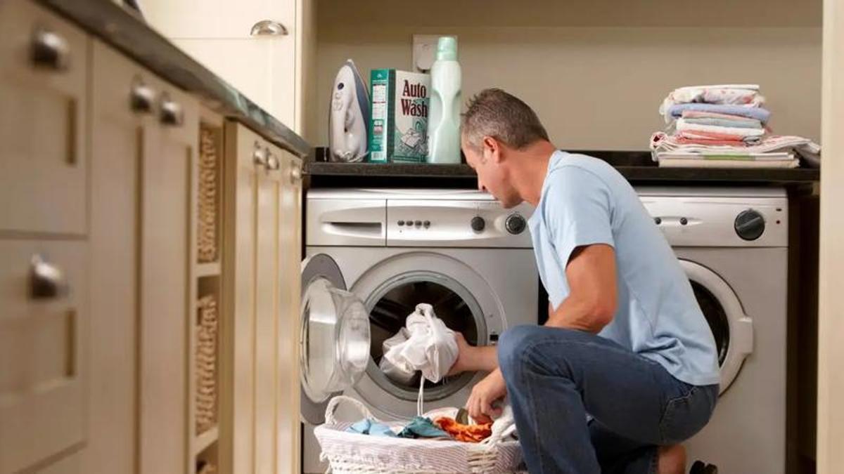 Un hombre sacando la ropa de la lavadora
