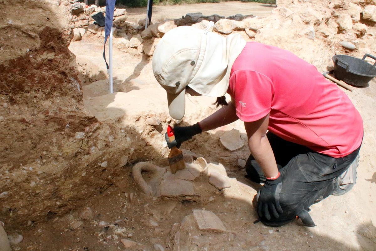 Una arqueòloga netejant els fragments d'àmfora que s'han trobat en una de les cases primigènies del barri portuari de la Neàpolis