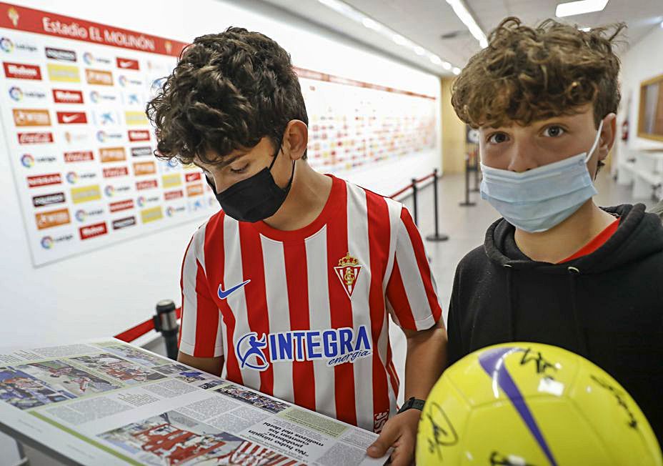 Por la izquierda, Pelayo y Álex Vigil Mon, en la sala de prensa de El Molinón, ante la reproducción de su reportaje en LA NUEVA ESPAÑA. | M. León