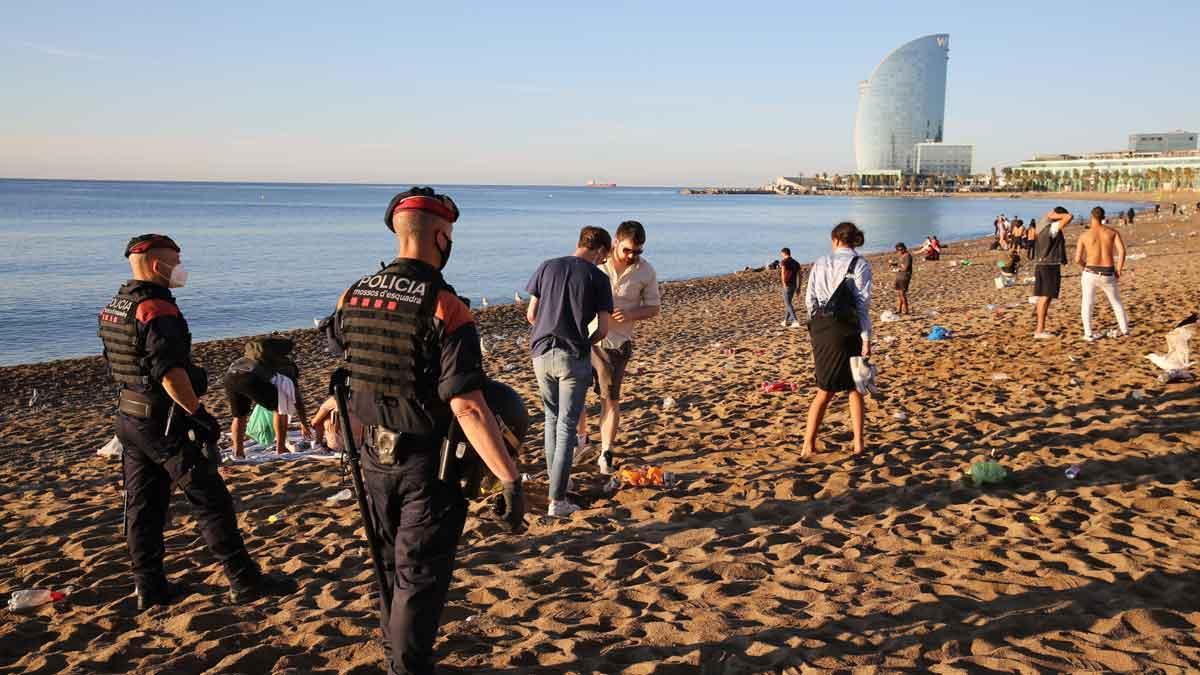 Agentes de los Mossos despejan la playa de la Barceloneta a primera hora de la mañana, tras la verbena de Sant Joan.