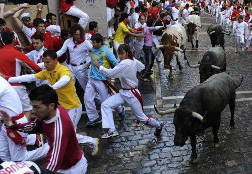 Runners sprint in front of Adolfo Martin fighting bulls on Estafeta corner during the seventh running of the bulls of the San Fermin festival in Pamplona