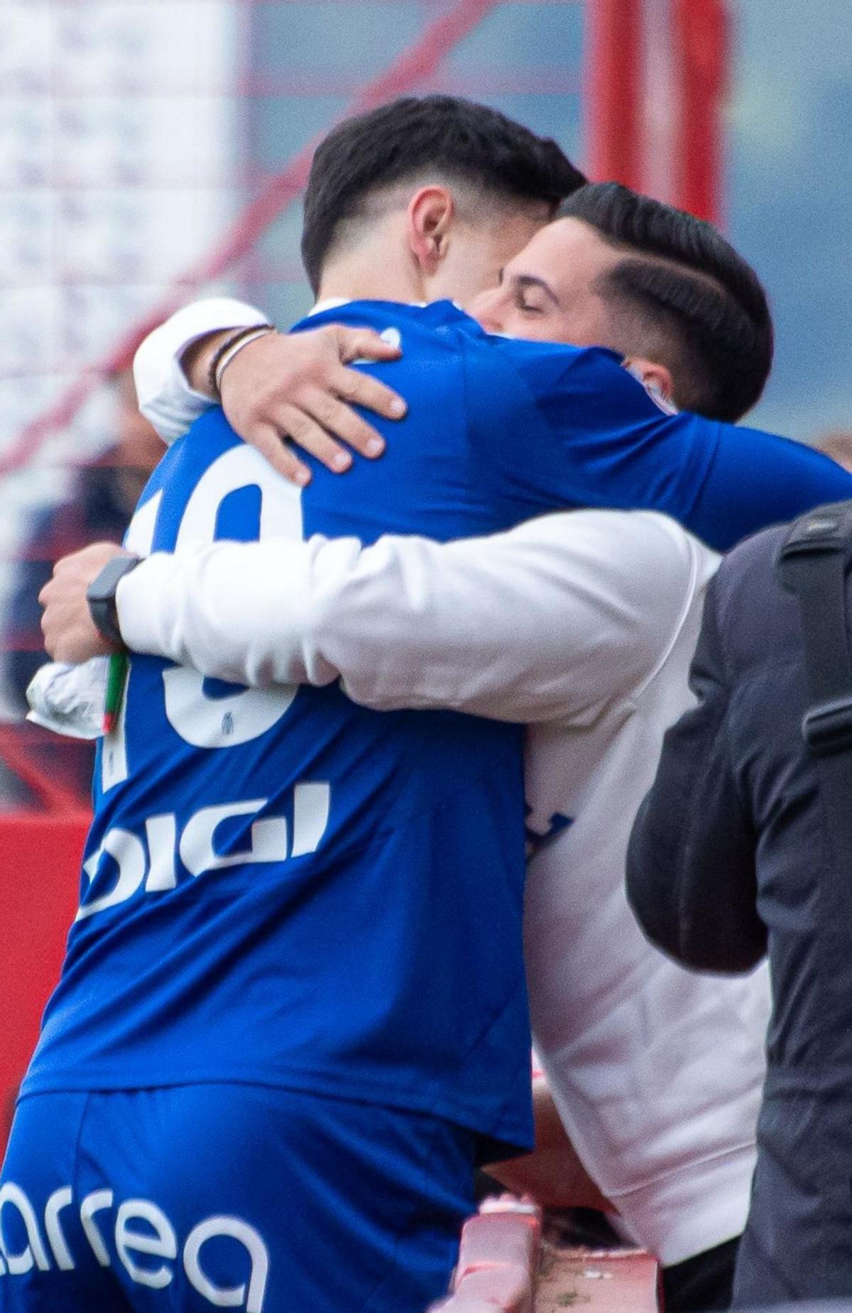 Joaquín Delgado y Manuel Jiménez se abrazan tras un gol del ariete ante el Sporting en Mareo. En los detalles, el goleador tras firmar con el Barça B y junto a su mejor amigo de pequeños. | ANA VÁZQUEZ / BARÇA / LNE