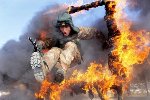 A frontier soldier from the People's Liberation Army jumps through a ring of fire as part of training in Heihe