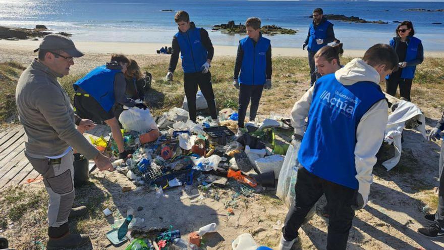 Voluntarios retirando basura de la playa de Raeiros.   | //  FDV
