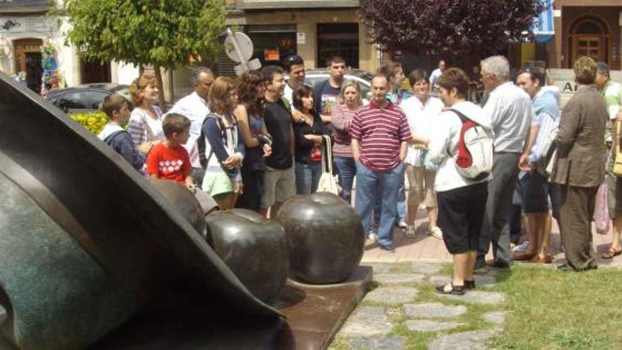 Un grupo de turistas, junto a la escultura de la manzana, en Villaviciosa.