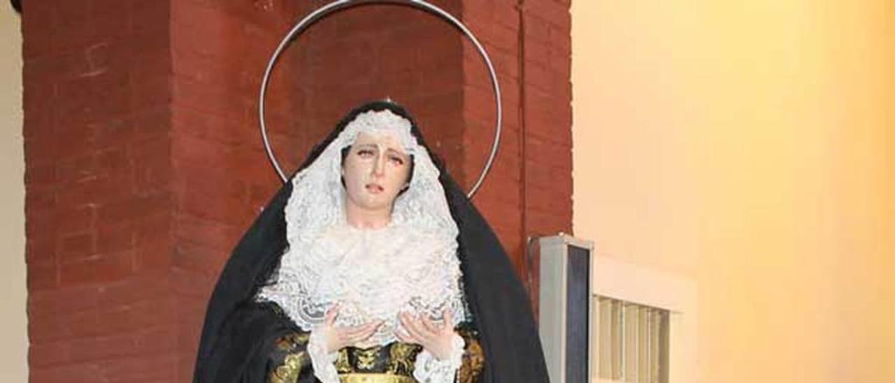 Rosi Menéndez junto a la Virgen, colocada sobre el cajón de los donativos, ayer, en Lugones.