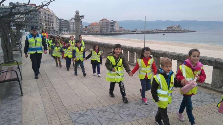 Los niños, acompañados por un agente y docentes, durante el trayecto por el paseo de Silgar. // FdV