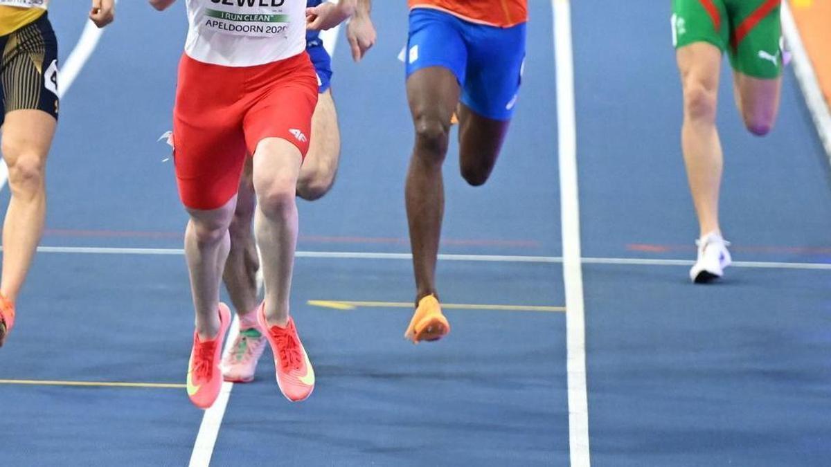 Unos atletas durante una carrera en una pista de atletismo.