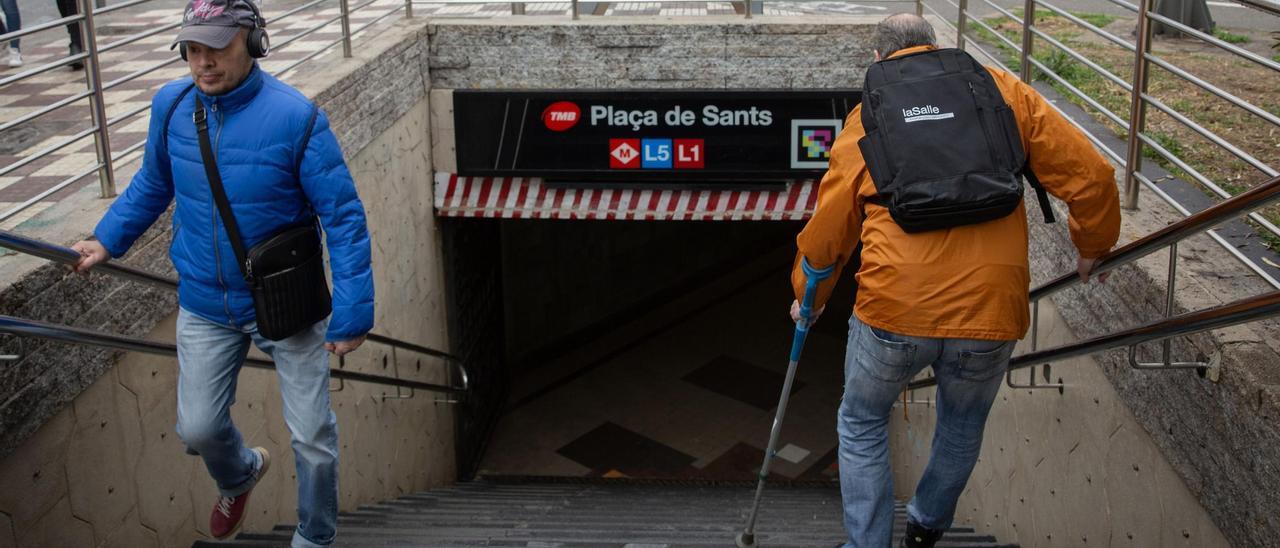 Gustavo -a la derecha- baja al metro con una muleta en Plaça de Sants, una de las paradas del metro de Barcelona sin ascensores.