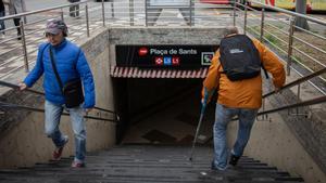 Gustavo -a la derecha- baja al metro con una muleta en Plaça de Sants, una de las paradas del metro de Barcelona sin ascensores.