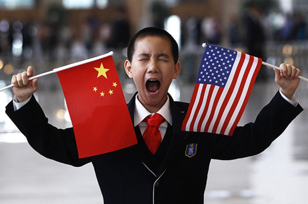 Un nen petit amb banderes dels EUA i de la Xina espera per saludar el Secretari d’Estat dels EUA, Hillary Clinton, al Museu Nacional de Pequín.