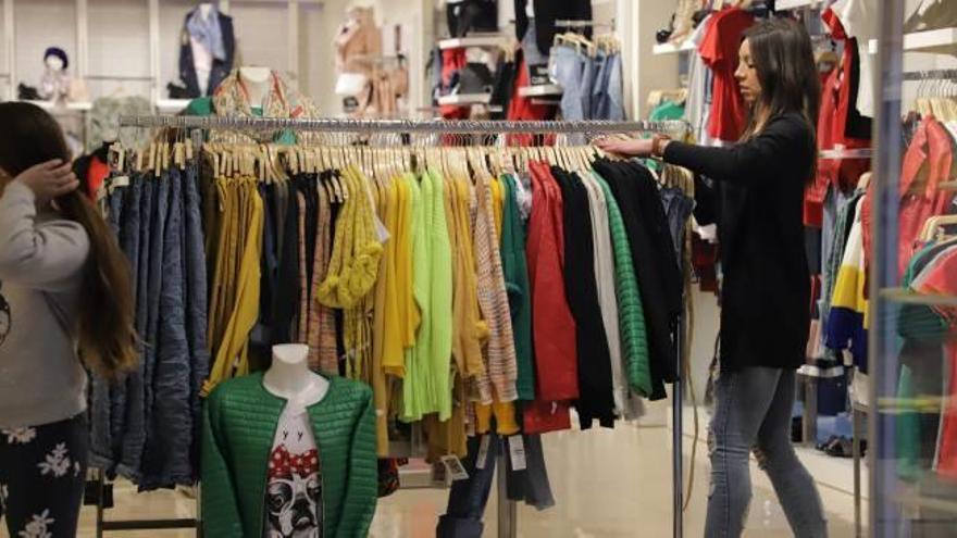 Una dependienta arrastra una percha llena de ropa en una tienda del Centre Històric de Gandia.