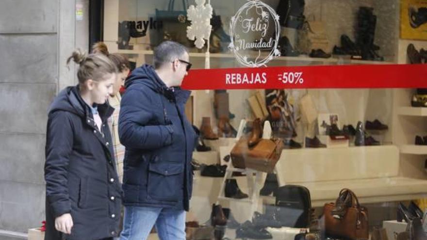 Varios viandantes observando ayer un cartel de rebajas en un comercio del centro.