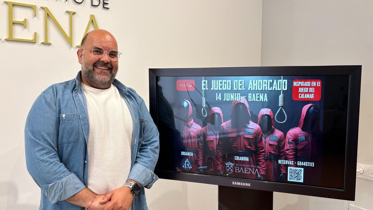 El concejal de Juventud de Baena, José Domingo Castro, junto a una pantalla con la imagen promocional de El juego del ahorcado.
