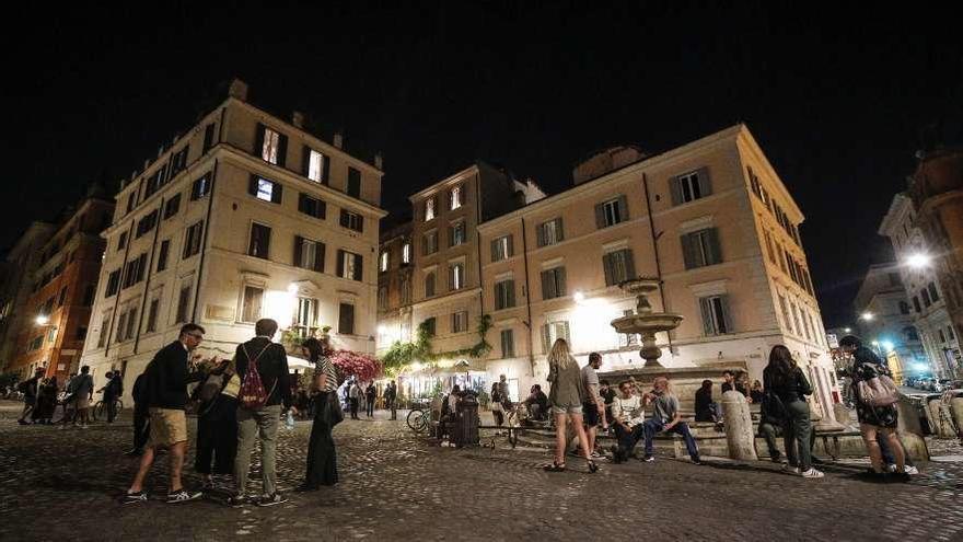 Varios grupos de personas se reúnen de noche en una plaza del Trastévere de Roma. // Efe