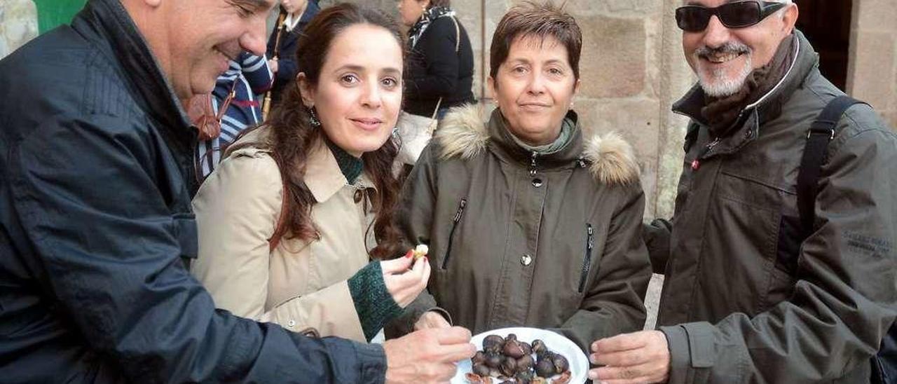 Unos turistas comen unas castañas en un magosto en el casco histórico de Combarro. // Rafa Vázquez