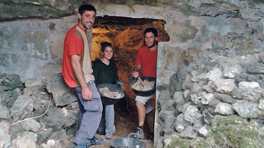 Los voluntarios sacan capazos con piedras del interior de la gruta.