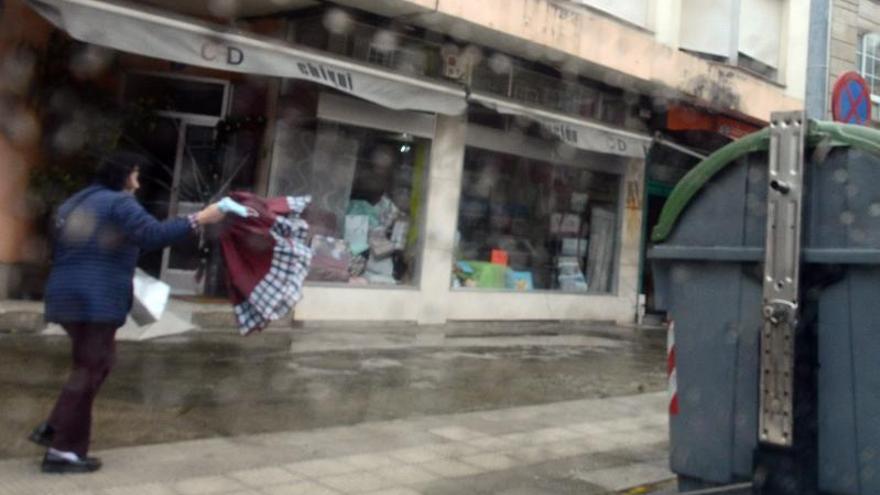 Una mujer observa su paraguas roto por la fuerza del viento, esta semana en el centro de Cangas. |   // Gonzalo Núñez