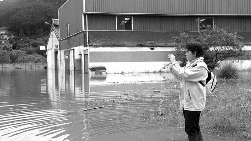 Una vecina fotografía una de las zonas afectadas por las últimas inundaciones en la parroquia de Veriña.