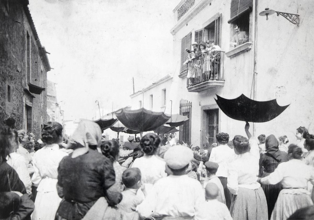 Un grup de persones esperant per aconseguir confits i llaminadures després d’un bateig a Can Masferrer, a principis del segle XX.