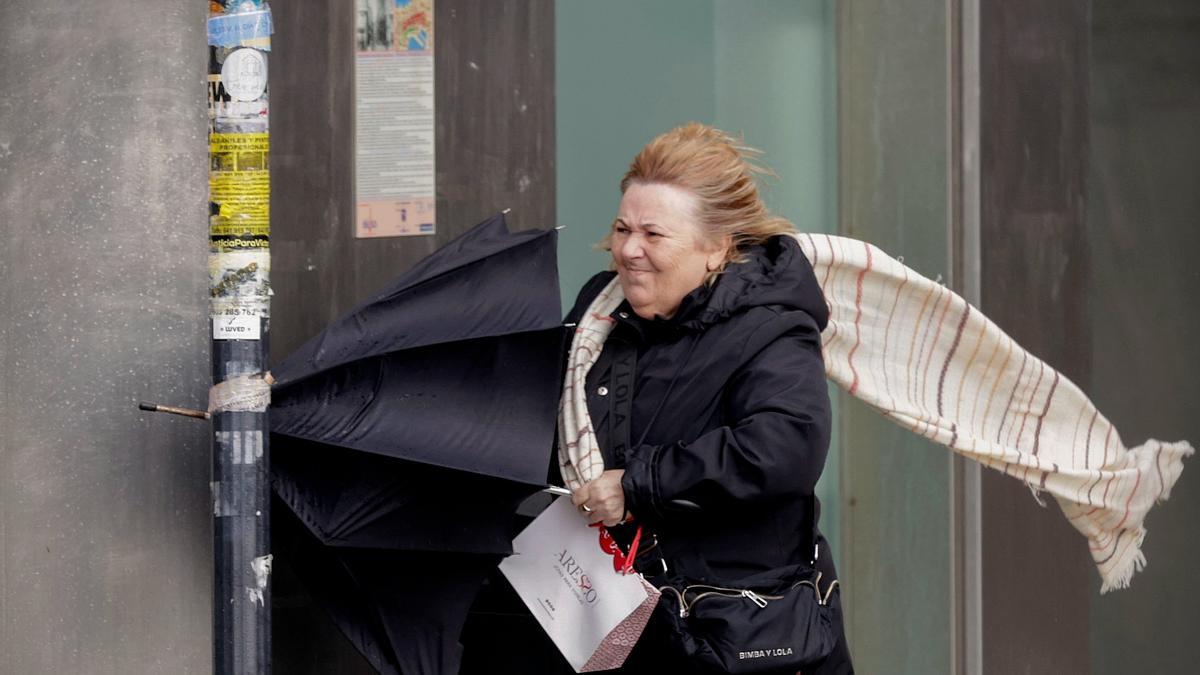 Una mujer se resguardaba de la fuerza del viento en A Coruña, este jueves.