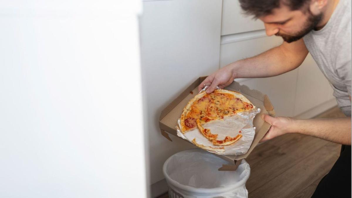Un home tirant la meitat d’una pizza a les escombraries.  | DIARI DE GIRONA