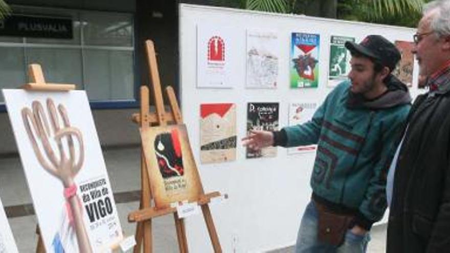 Cándido Pérez y Emilo García, ganador de un accésit, observan los carteles en la exposición de la lonja del Concello.  // Ricardo Grobas