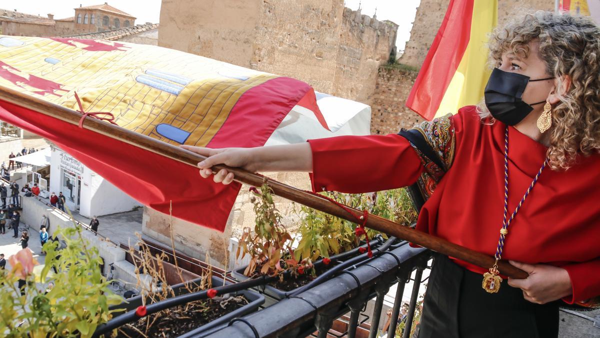 La concejala más joven, Paula Rodríguez, tremola el pendón de San Jorge desde el balcón del ayuntamiento.