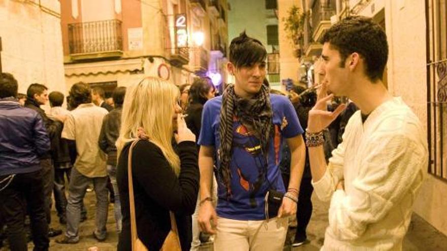 Un grupo de jóvenes fuma en la puerta de uno de los pubs del Barrio de Alicante.