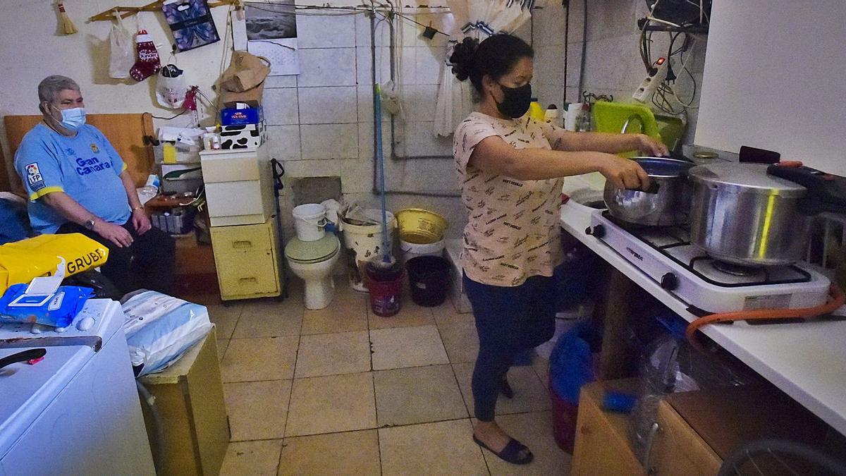 Guacimara Saavedra, haciendo la comida con una cocina de gas, y su padre, Carmelo Saavedra, sentado en la cama. | | ANDRÉS CRUZ