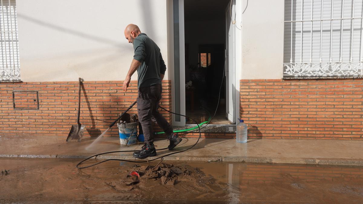 Una persona intenta sacar el barro fuera de una vivienda en Roca de la Sierra