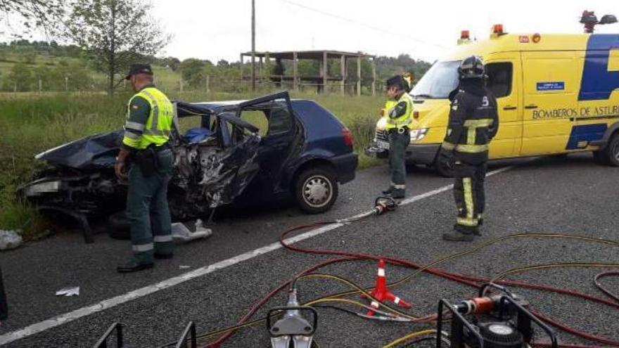 Guardia Civil y bomberos junto a uno de los vehículos siniestrados en el accidente de Nava.