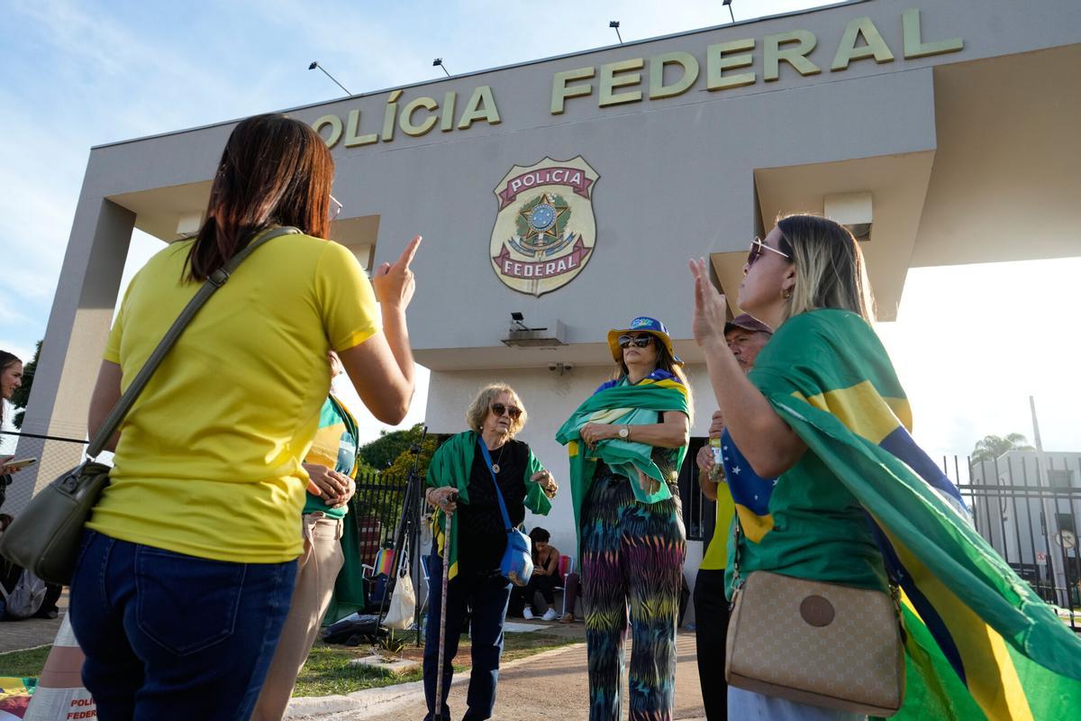 Supporters of Brazil's former President Jair Bolsonaro pray outside the Federal Police headquarters where Bolsonaro is being held in Brasilia, Brazil, Saturday, Nov. 22, 2025. Brazil's Federal Police arrested Bolsonaro preemptively on Saturday, days before he was due to start serving his 27-year-plus prison sentence for leading a coup attempt. (AP Photo/Eraldo Peres)