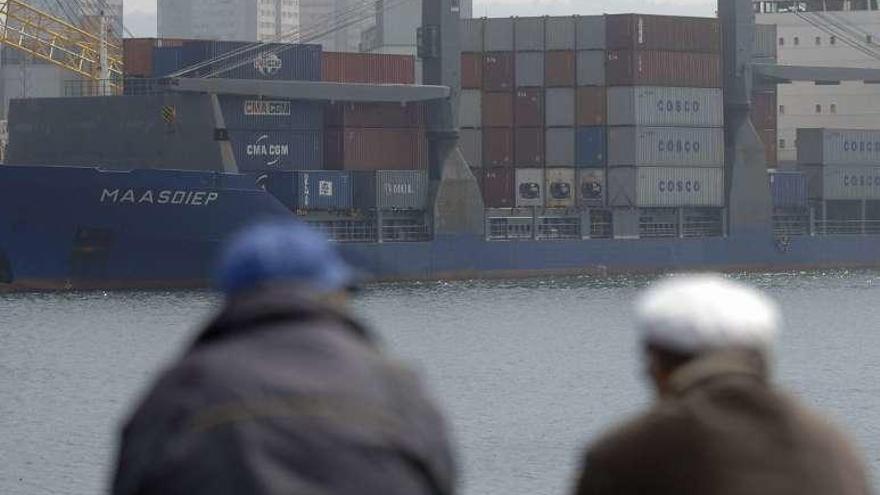 Dos hombres observan la descarga de un barco en el puerto.