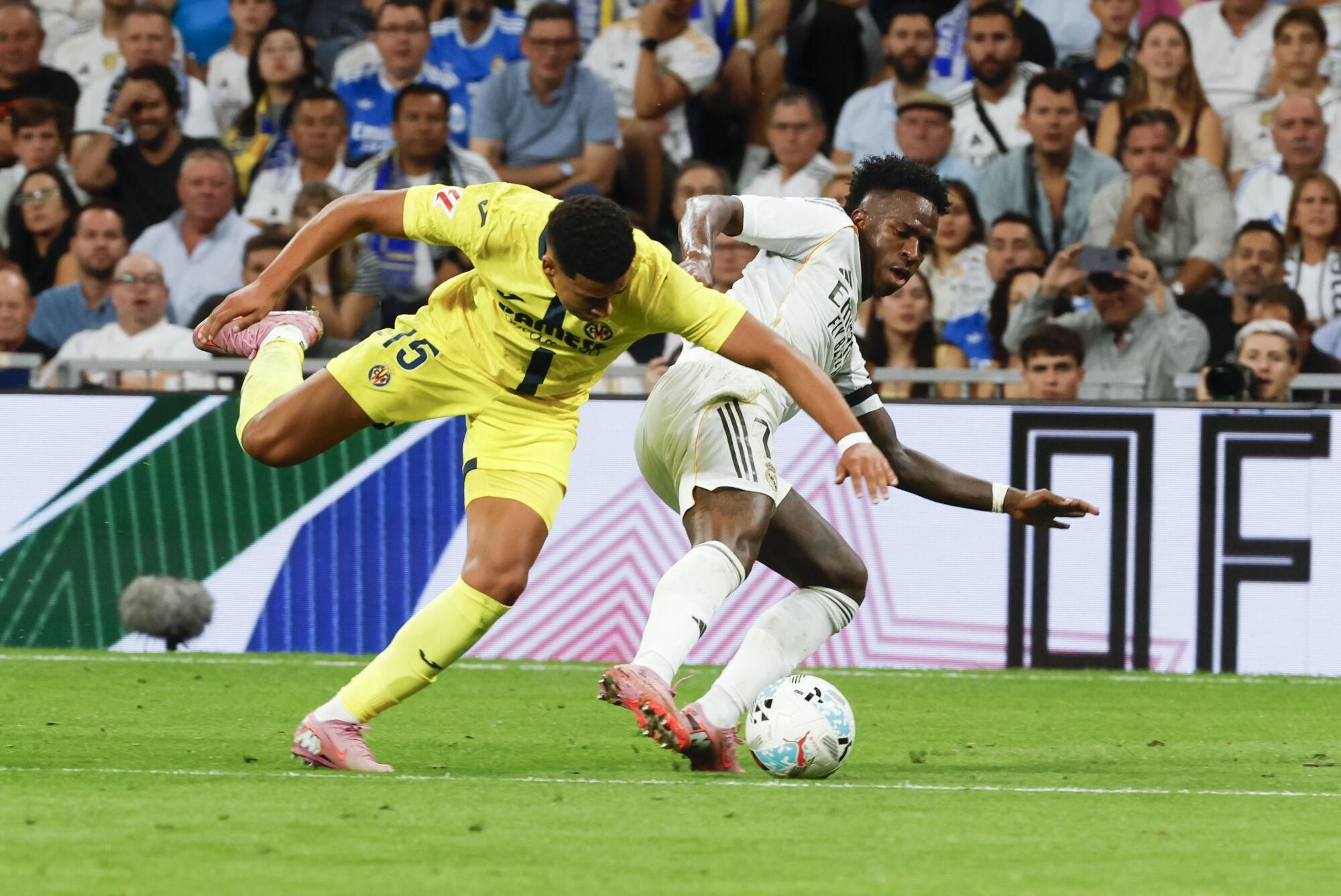 MADRID, 04/10/2025.- El delantero del Real Madrid Vinicius Junior (d) juega un balón ante Santaigo Mourinho, del Villarreal, durante el partido de LaLiga de fútbol que Real Madrid y Villarreal disputan este sábado en el estadio Santiago Bernabéu. EFE/Guillén