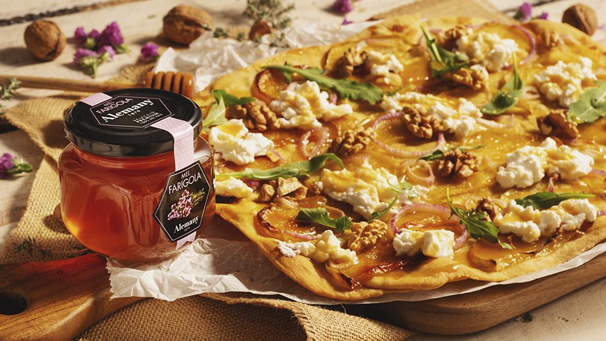 La miel de tomillo Alemany aporta un matiz balsámico y ligeramente herbal a una coca salada con queso y nueces, ejemplo del potencial gastronómico del producto más allá del desayuno.