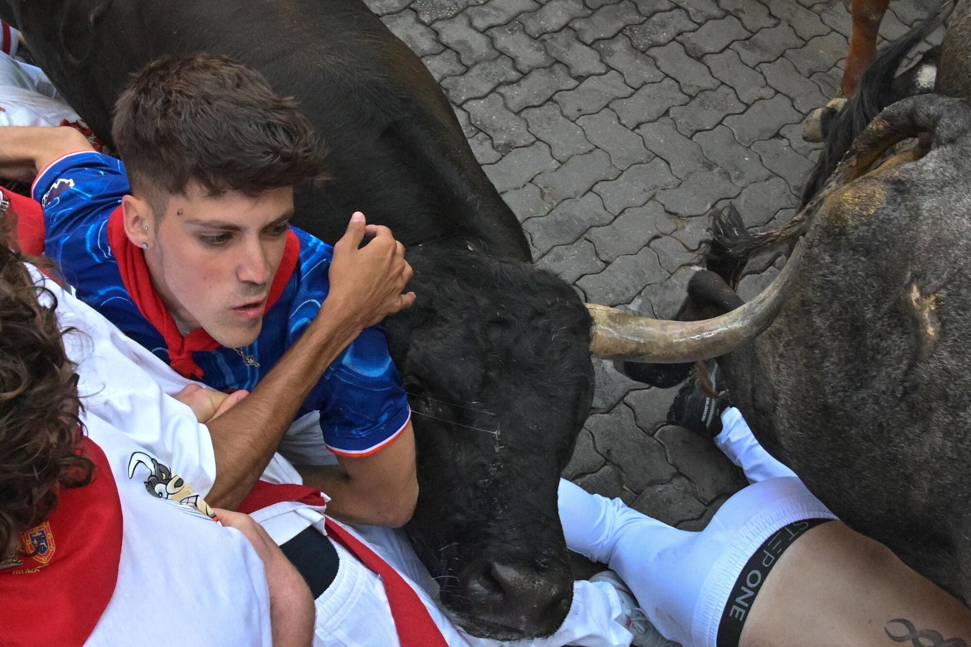 PAMPLONA, 14/07/2025.- Uno de los toros embiste a uno de los mozos durante el octavo y último encierro de los Sanfermines este lunes. EFE/ Daniel Fernández