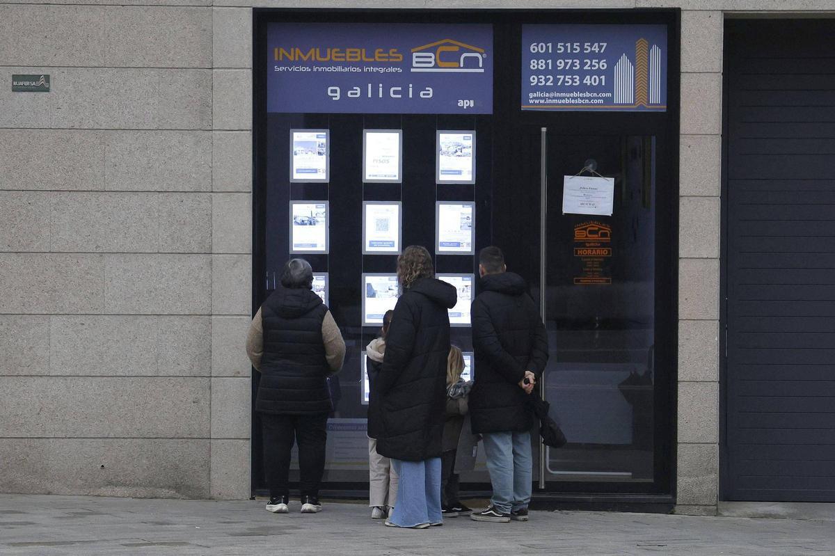 Varias personas miran los anuncios de una inmobiliaria con viviendas en alquiler en Santiago de Compostela