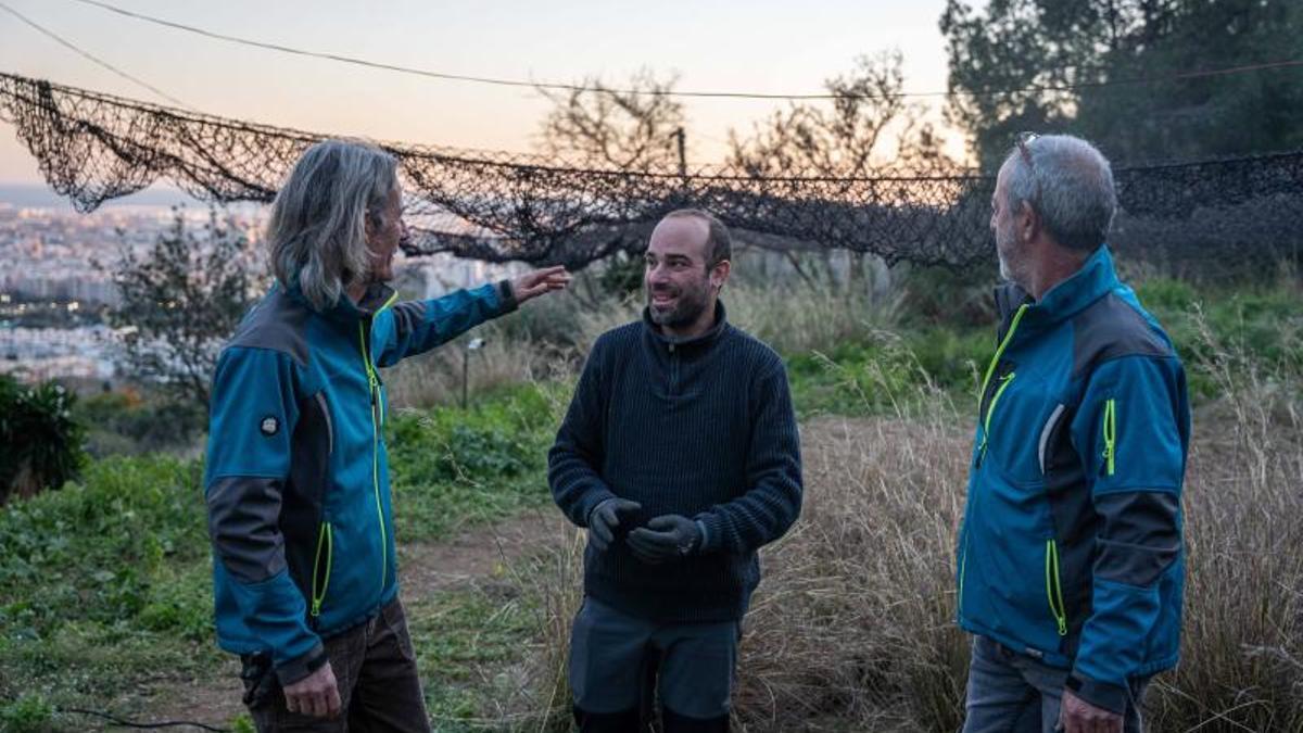 Enric Ullar, Oriol Molero y Santi Oms, de la empresa Estrateko, delante de la red que han ideado para capturar a jabalís sin causarles daño.