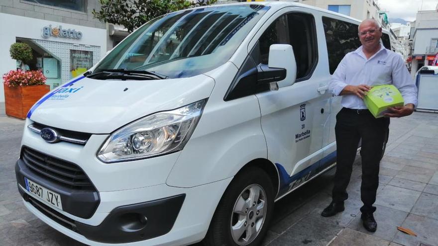 José Gómez, junto a su taxi, muestra el desfibrilador.